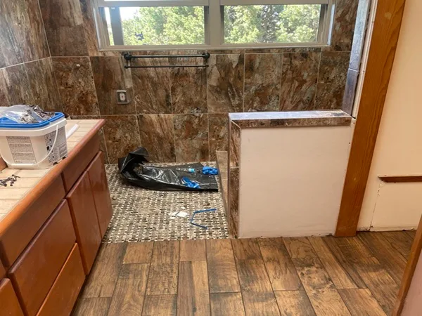 Complete bathroom transformation featuring new walk-in shower with floor-to-ceiling tile, replacement of outdated glass block window with modern double-hung windows. Spacious, modern design.